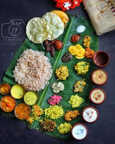 an assortment of food is laid out on a banana leaf