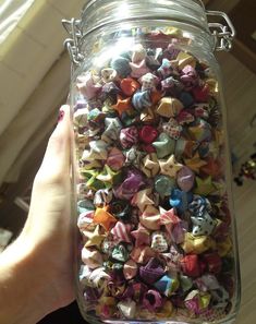 a person is holding a jar full of small bows