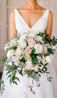 a bride holding a bouquet of white and pink flowers