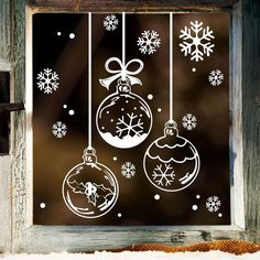 a window decorated with christmas ornaments and snowflakes hanging from it's side