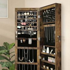 a wooden jewelry cabinet with lots of necklaces and rings on it's doors