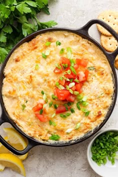 an omelet in a cast iron skillet topped with tomatoes and green onions