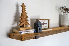 a wooden shelf with some books and a small house on it, next to a christmas tree