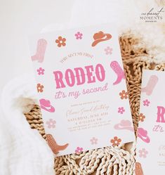 two pink and white wedding cards sitting on top of a woven basket next to each other