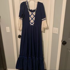 a blue dress hanging on a door with white laces and crochet trim