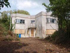 an abandoned house with boarded up windows and no doors on the outside, surrounded by trees