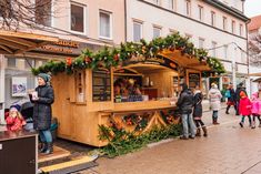 people are walking around in front of a food stand with christmas decorations on the outside