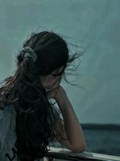 a woman with her hair blowing in the wind while sitting on a boat looking out to sea