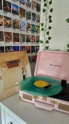 a record player sitting on top of a table next to a wall covered with pictures