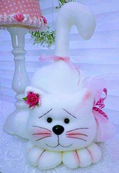 a white cat sitting next to a pink lamp