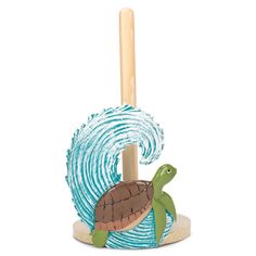 a small toy turtle on top of a wooden pole with a wave in the background