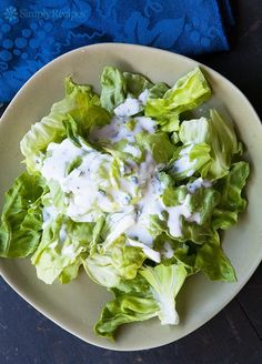 a white plate topped with lettuce covered in dressing