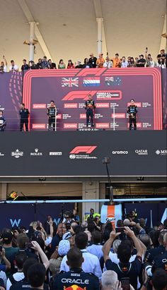 a crowd of people standing on top of a red and black stage next to each other