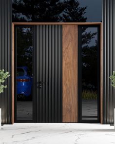 a blue car is parked in front of a black building with wooden doors and sidelights