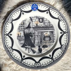 the plate is decorated with an image of a witch and her cat in front of a fireplace