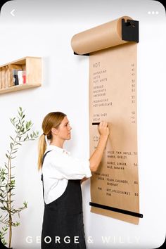 a woman standing in front of a wall with a large poster hanging on it's side