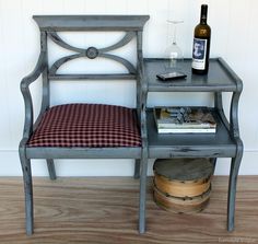 a small table with a bottle of wine on it next to a chair that has a checkered seat