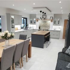 a modern kitchen and dining room are shown in this image, with the center island table surrounded by gray chairs