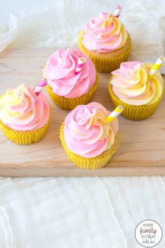 cupcakes with pink and yellow frosting on a wooden tray