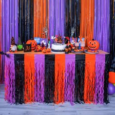 the table is decorated with orange, black and purple streamers as well as halloween decorations