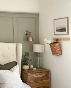 a white bed sitting next to a wall with a basket on it's headboard