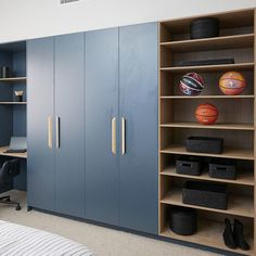 a bedroom with blue cabinets and basketballs on the shelves