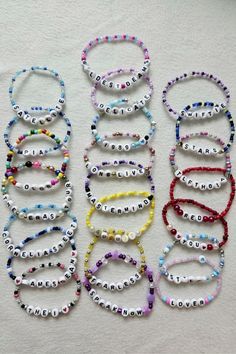 several bracelets with words on them are arranged in different colors and sizes, including beads