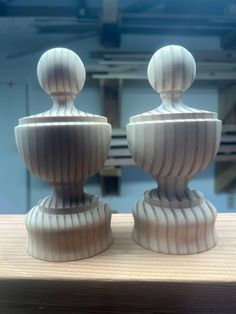 two white vases sitting on top of a wooden table