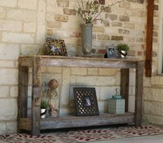 a wooden shelf with pictures on it next to a brick wall and potted plant