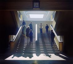 people are walking up and down the stairs in an office building with sunlight streaming through