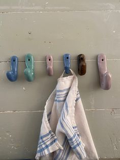 towels hanging on hooks in front of a wall