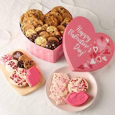 three valentine's day cookies and two heart shaped cookies in a pink gift box