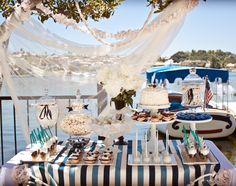 a table topped with cakes and cupcakes next to a body of water