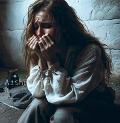 a woman is sitting on the floor with her hands clasped to her face and eyes closed