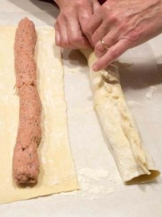 a person is kneading dough with a long sausage stick on top of it