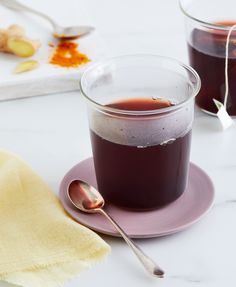 two glasses of liquid sitting on top of a plate next to a spoon and napkin