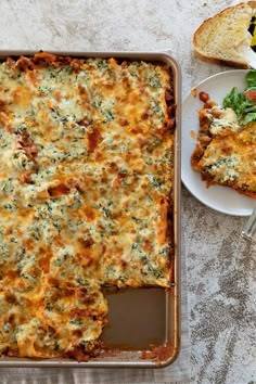 a casserole dish with cheese and spinach on it next to a slice of bread