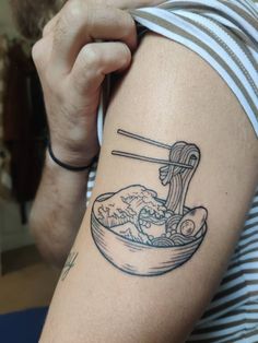 a woman with a tattoo on her arm eating noodles