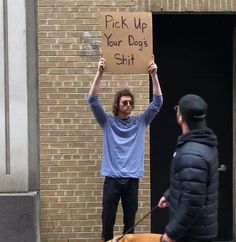 a man holding up a sign while standing next to a dog