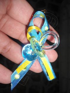 a hand holding a small blue and yellow ribbon