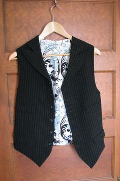 This is our latest vest style. Four pockets and wide peak lapels made for a unique look. This vest is vegan safe, cut from a stunning rayon/poly pinstripe fabric and lined in cotton with skull motifs. But you can choose from hundreds of fabrics including fine wools and silks. We can really make just about any type and style of vest that you can imagine. The matching tie and dress shirt shown in the pics are not included with this price, but we can make those also. Just contact us so we can get s Pinstripe Fabric, Vest Style, Peak Lapel, Sport Coats, Vest Fashion, Denver Co, Sport Coat, Mens Suits, Dress Shirt