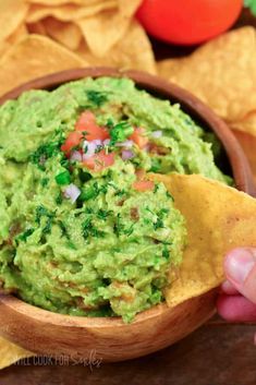 a wooden bowl filled with guacamole and tortilla chips