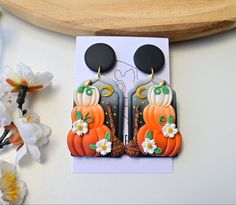 the earrings are decorated with pumpkins and daisies on top of a white card