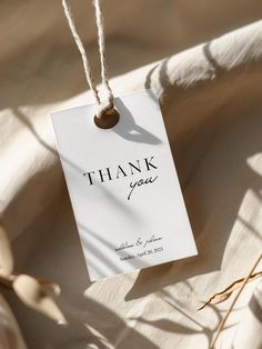 a thank card hanging from a string on top of a table with dried flowers in the background