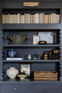 a bookshelf filled with lots of books next to a vase and other items