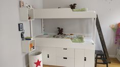 a white bunk bed sitting next to a wall with stuffed animals on top of it