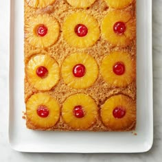 pineapple upside down cake on a white plate with red cherries around the edges