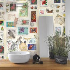 a bathroom wall covered in lots of stamps and flowers next to a sink with a mirror above it