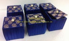 four blue boxes with gold designs on them sitting on a white table top next to each other