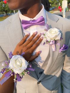 a man in a suit and bow tie with flowers on his lapel